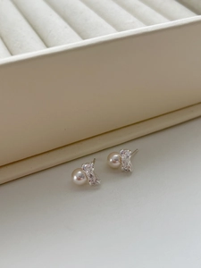 Close-up of elegant 925 silver bow stud earrings featuring white pearls and zircon stones