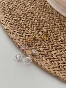 Gros plan sur les boucles d'oreilles nœud pretzel en or et argent avec zircons