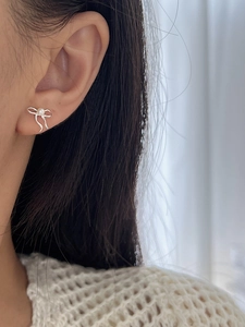 Détail des boucles d'oreilles nœud en argent 925 avec perle sur l'oreille du modèle