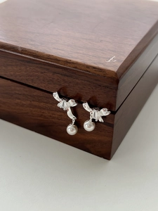 Close-up of S925 silver bow stud earrings with zircon and dangling white pearls