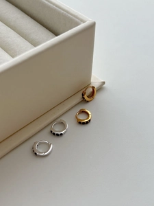 Macro detail of S925 silver hoop earrings with black zircon stones in gold and silver