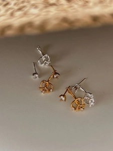 Gros plan sur des boucles d'oreilles cœurs entrelacés en or et argent avec zircons
