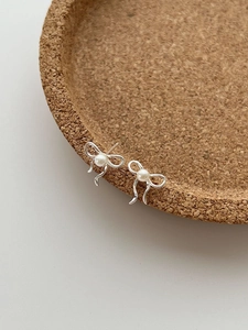Vue détaillée des boucles d'oreilles nœud en argent 925 avec perle sur support en liège