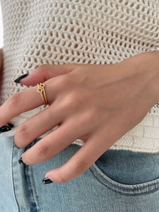 Detail of double-layer twisted golden wave ring worn with stylish casual outfit