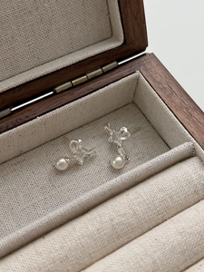Close-up of S925 sterling silver butterfly stud earrings with elegant white hanging pearls