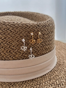 Détail de boucles d'oreilles cœur bretzel en argent 925 avec zircons sur chapeau de paille