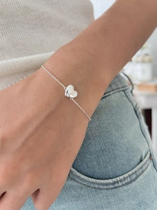 Detail of 925 sterling silver heart bracelet with small white pearl on wrist