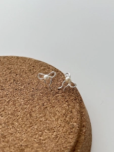 Détail de boucles d'oreilles nœud en argent 925 avec perle sur support en liège