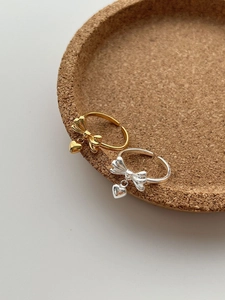 Detailed close-up of S925 sterling silver bow rings with small heart charms in gold and silver