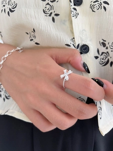 Detailed view of silver bow ring with zircon gemstone and beaded band on model hand