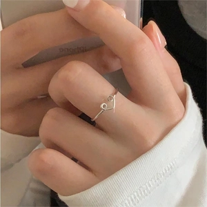 Detailed view of a minimalist 925 silver open heart ring worn on a person's finger