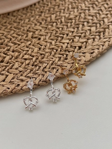 Gros plan de boucles d'oreilles cœurs entrelacés en or et argent serties de cristaux