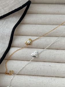 Detail shot of gold and silver heart necklaces with pearls on a textured jewelry tray