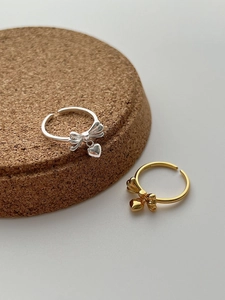 Close-up of S925 sterling silver bow ring with heart pendant in silver and gold finish