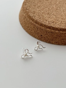 Détail rapproché de boucles d'oreilles nœud en argent 925 avec une perle blanche centrale