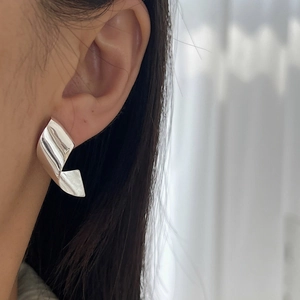 Minimalist 925 sterling silver twisted ribbon hoop earrings worn by a model