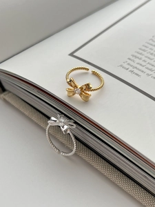 Close-up of gold and silver bow rings with twisted bands and sparkling zircons