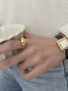 Polished gold teardrop ring paired with a vintage square watch on a model's hand