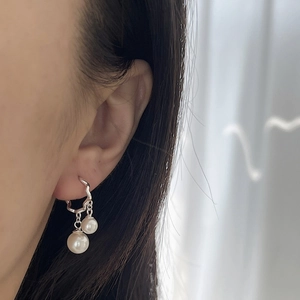 Orecchini a cerchio in argento 925 con perle pendenti indossati da una modella
