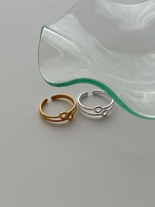 Detail of twisted double-layered open rings in gold and silver finish on gray background