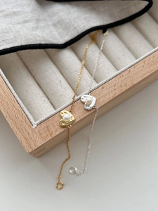 Close-up of gold and silver heart-shaped pearl bracelets on a wooden jewelry organizer