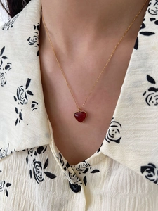 Close-up of a 925 sterling silver necklace with a red heart pendant worn by a model