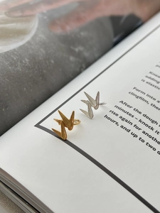 Detailed close-up of textured gold and silver bamboo leaf open rings on a magazine