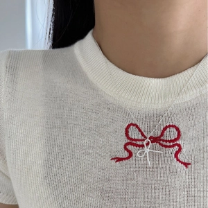 Elegant silver bow pendant necklace with micro-pave crystals on a white knit sweater