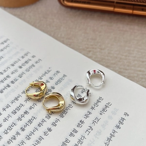 Boucles d'oreilles créoles torsadées dorées et argentées sur pages de livre