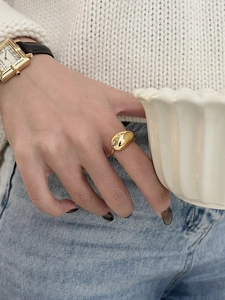 Close-up of a chunky golden teardrop ring with fluid metal design on a model's hand