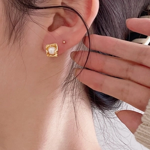 French vintage style square gold frame pearl earrings worn by a model in a close-up view