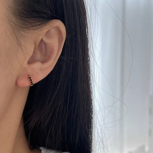 Minimalist gold hoop earring with black zircon pavé stones shown on model