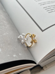 Detailed shot of two-tone bow ring with gold twisted band and inlaid zircons on book