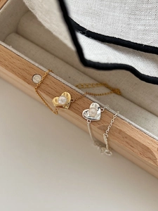 Detail of adjustable heart pendants with pearls in gold and silver finishes