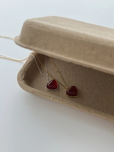 Detail of red heart pendants on gold and silver chains inside a craft jewelry box