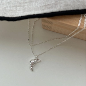Polished silver croissant pendant necklace with minimalist chain on a neutral background