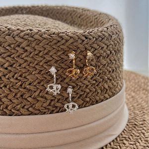 Boucles d'oreilles nœuds étincelantes or et argent avec zircons sur chapeau paille