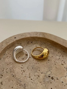Detailed view of teardrop rings in gold and silver finish on a stone tray