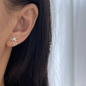 Élégantes boucles d'oreilles nœud en argent 925 avec perle blanche portées sur l'oreille
