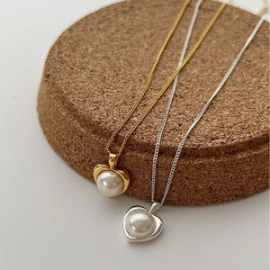 Elegante collana a cuore oro e argento con grandi perle su espositore in sughero
