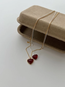Detailed close-up of gold and silver heart necklaces with red enamel on a gift box
