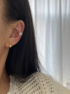 Detailed view of a gold floral ear cuff with moonstone and heart stud on ear