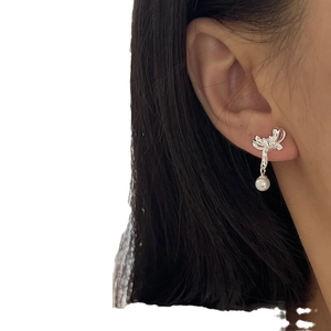 Elegant silver bow earrings with hanging pearl charm shown on model ear