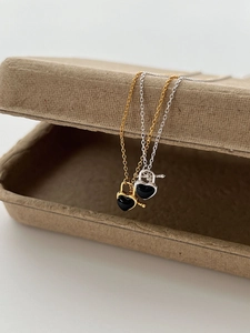 Detail of silver and gold OT buckle necklaces with black heart pendants on craft box