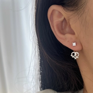 Boucles d'oreilles clous en argent 925 avec nœud de bretzel et zircons portées à l'oreille