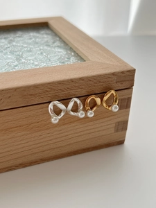 Detail of Mobius loop earrings in gold and silver finish with white freshwater pearls