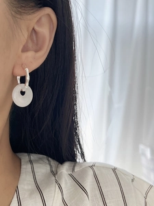 Detail of white agate peace buckle earrings with bamboo silver hoops worn by a model