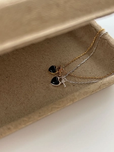 Close-up of gold and silver S925 heart necklaces with black agate and key pendants
