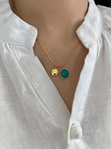 Detail of 925 silver gold necklace with round turquoise and gold textured disk pendants