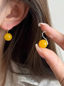Detail of 925 sterling silver hook earrings with round yellow agate bead on ear